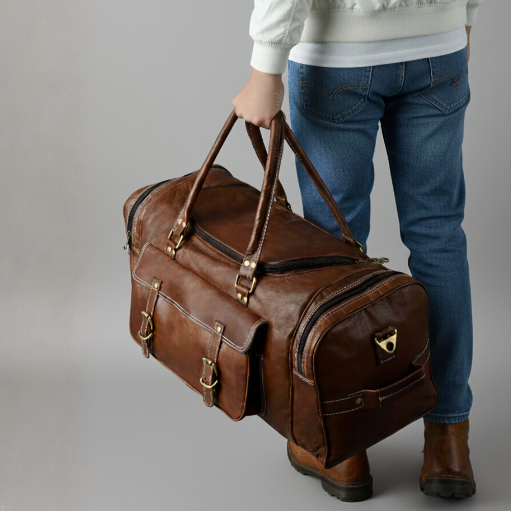 Person holding a brown leather duffel bag against a neutral background